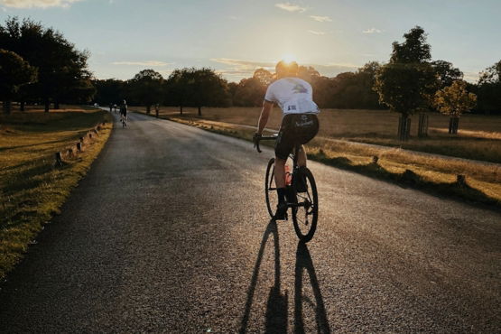 man in white shirt riding bicycle on gray asphalt road during daytime